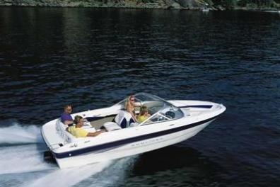 Speedboat with four passengers cruising on a lake with forested shoreline.