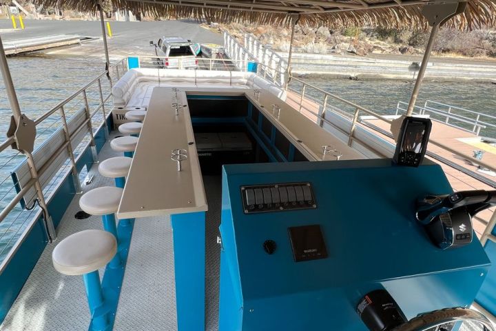 Interior of a boat with bar stools, counter, and steering wheel.