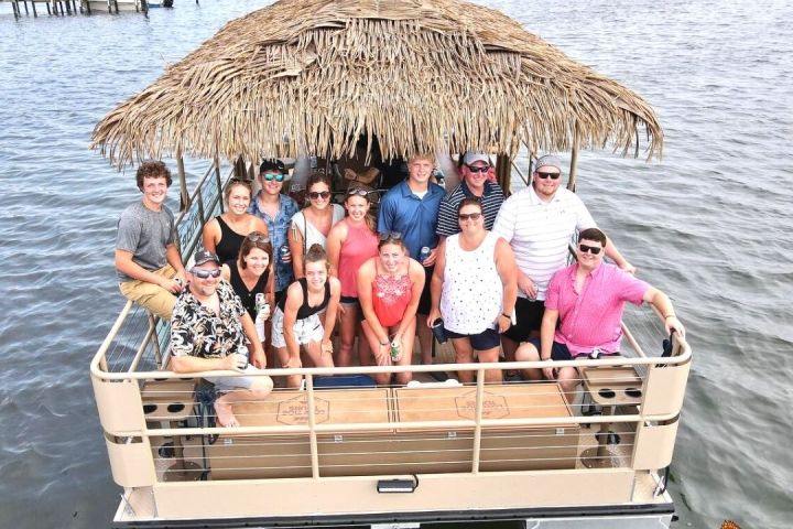 Group of people on a tiki-themed boat on the water in bright daylight.